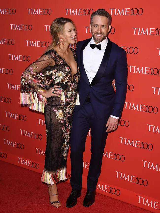 Couple posing on the red carpet at the TIME 100 Gala, woman in floral dress and man in navy suit with bow tie.