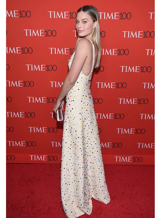 Woman in a sleeveless, embellished white gown at a Time 100 event, standing on a red carpet.