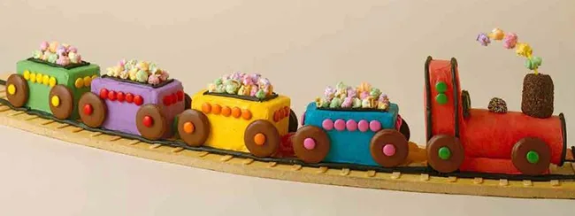 Colorful candy train with four wagons on a track, each filled with multicolored popcorn and decorated with round candies.