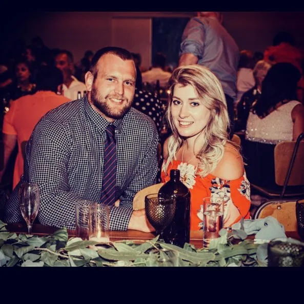A couple sitting at a decorated table during a social event, smiling at the camera.