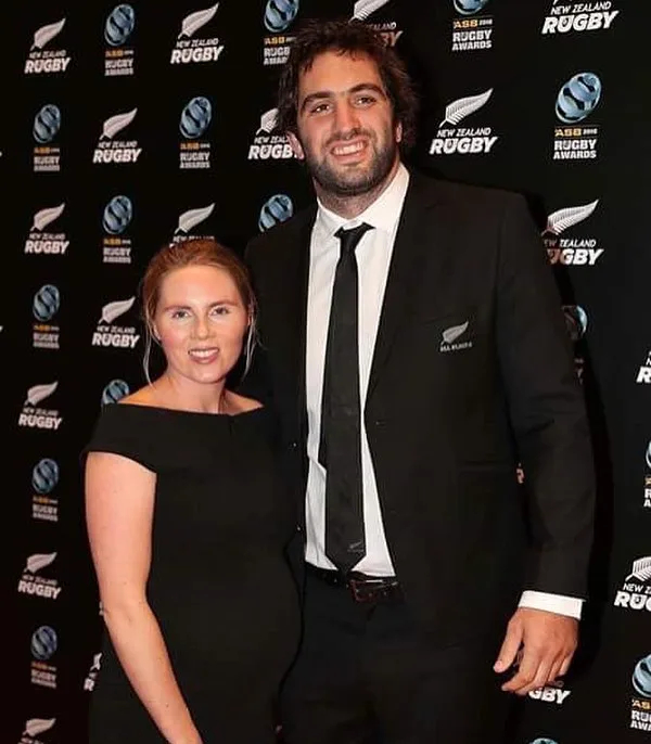 Man and woman posing at the New Zealand Rugby Awards. Man in a suit, woman in a black dress.