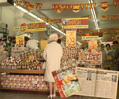 An elderly woman looks over some  of the bargain items in a grocery store in Auckland, 1968.
