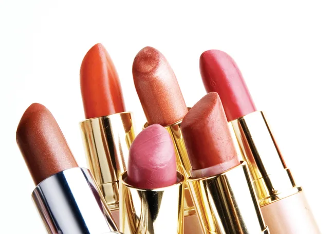 A collection of six lipsticks in various pink and red shades with gold casing, displayed close together.