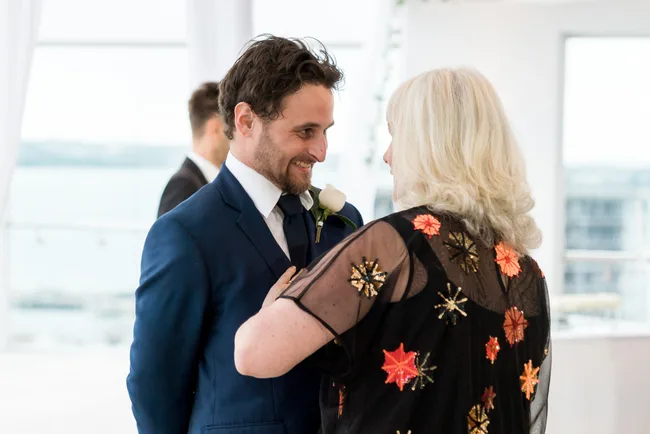 A man in a blue suit smiles at a woman with blonde hair in a sequined dress at a formal event.