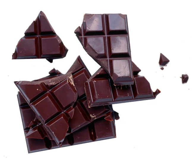 Broken pieces of dark chocolate bar on a white background.