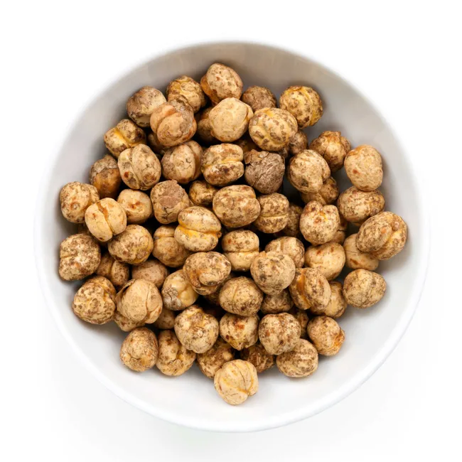 Bowl of dried tiger nuts on a white background.