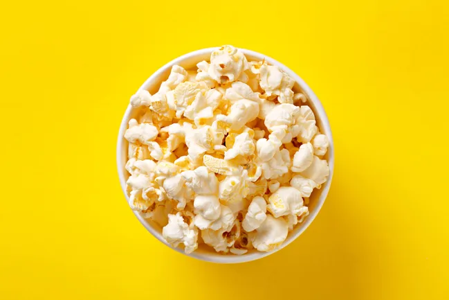 Bowl of popcorn on a bright yellow background.