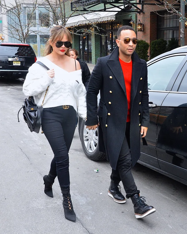 Couple walking on a city street, both wearing sunglasses and stylish clothing.