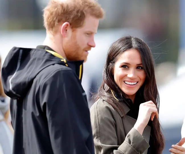 Two people outdoors, one smiling and wearing a dark coat, with soft focus in the background.