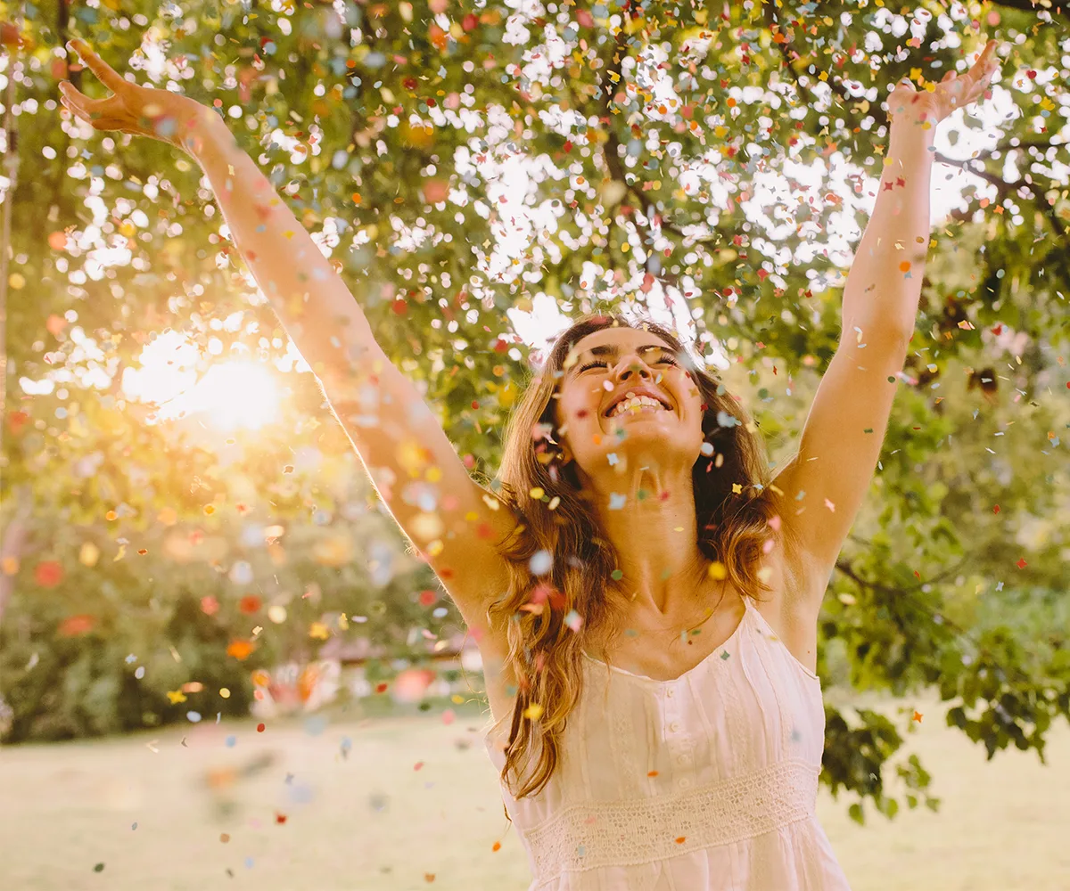 Happy woman throwing arms up in confetti