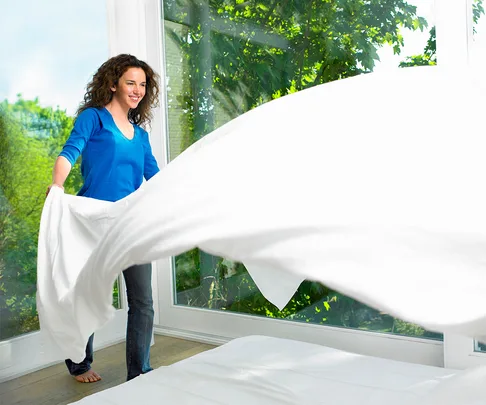 Woman making a bed on a crisp sunny day