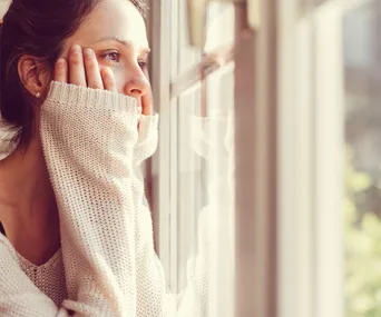 Bored woman looks out window 