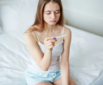 woman looking at pregnancy test worried