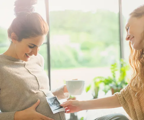 Pregnant woman holding sonogram over belly