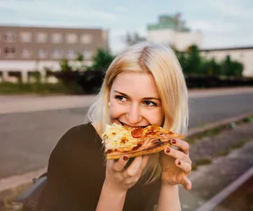 blonde woman happily eating pizza
