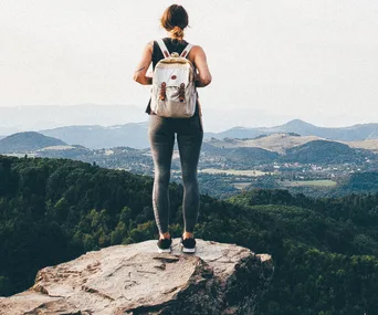 Casual female hiker looking out from summit over forest
