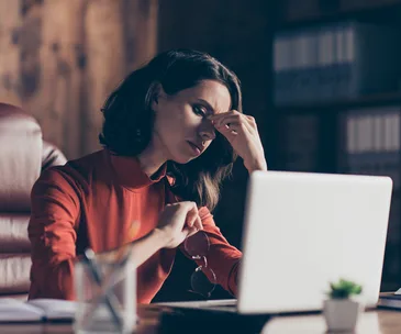 Tired business women staring at laptop glasses off rubbing nose