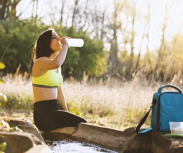 woman drinking water in a forest