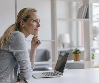 blonde woman sits at desk pensively relaxed