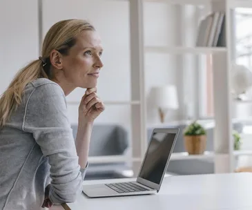 blonde woman sits at desk pensively relaxed