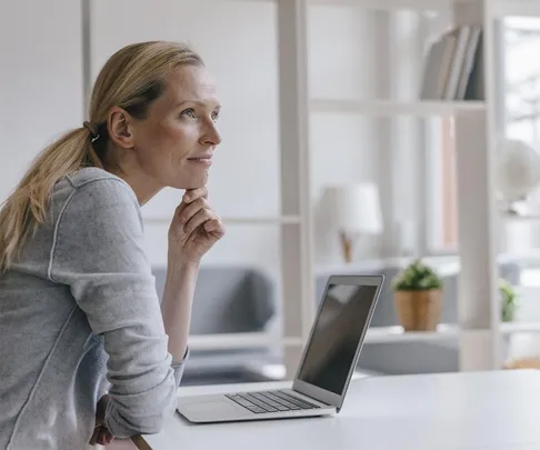 blonde woman sits at desk pensively relaxed