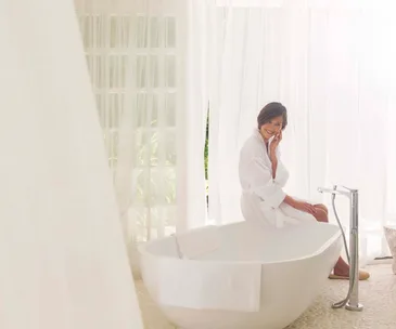 woman sitting by a bathtube in a bathrobe