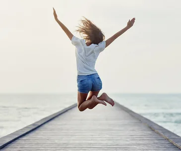 woman full of energy jumping on a pier