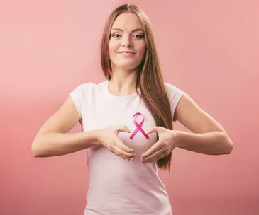 Woman holding hands in heart shape over breast