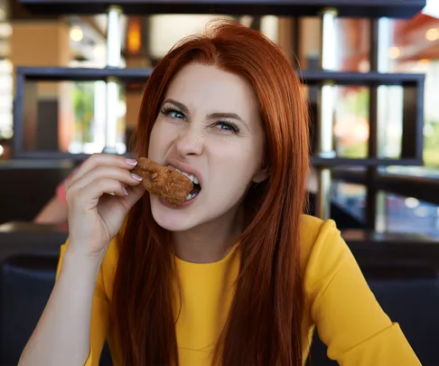 Woamn taking bite out of chicken wing