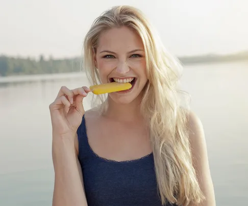 Smiling woman biting ice block
