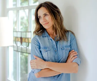 Mature woman leaning against wall deep in thought