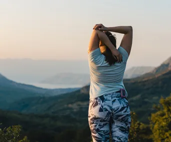 Woman with diabetes stretching on top of the hill