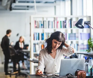 woman in an office staring at screen stressed