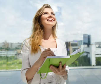 Young woman writing in notebook outside