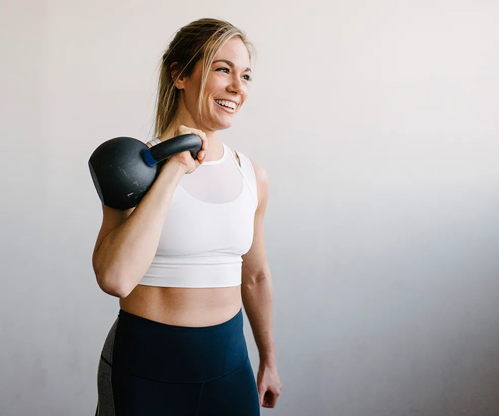 woman holding a kettle bell and smiling