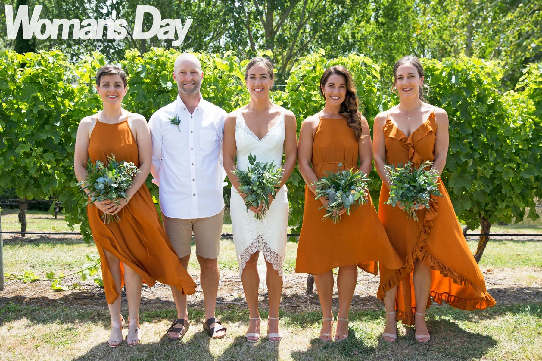 Emma's bride Charlotte standing in front of a grape vine with her bridesmaids on either side of her