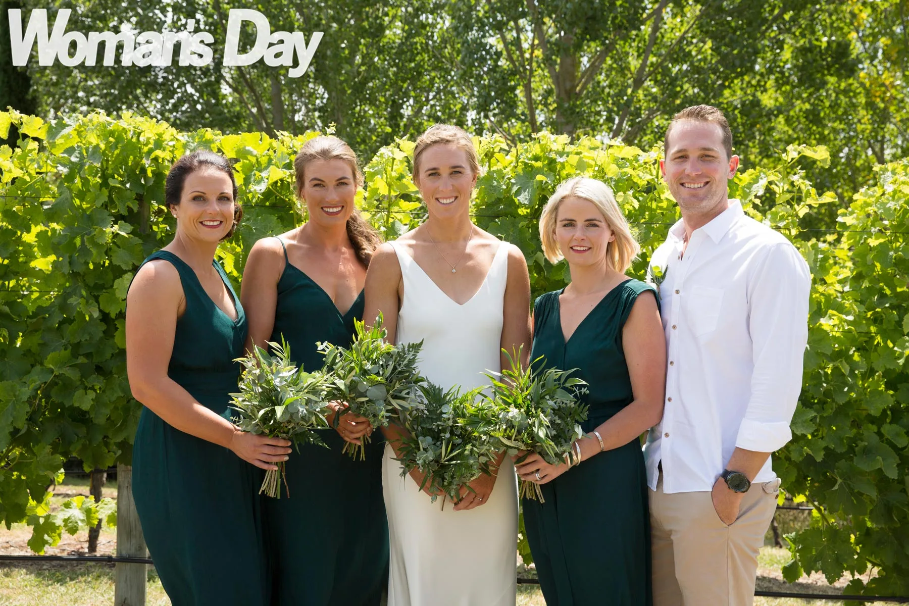 Emma Twigg standing in front of a grape vine with her bridesmaids (and one bride's man) on either side of her
