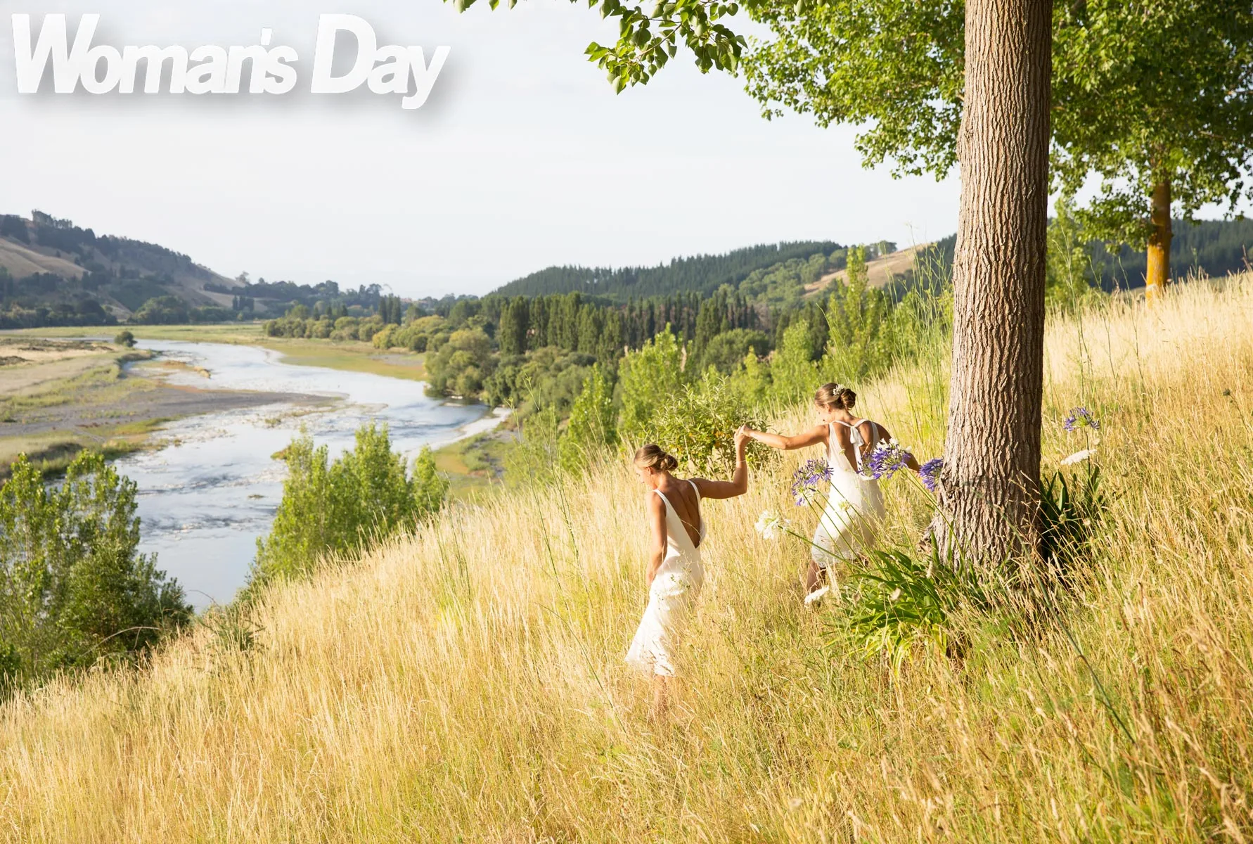 Emma and Charlotte standing in tall grass on their wedding day 
