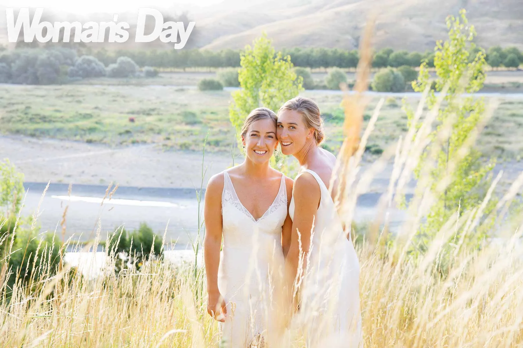 Emma and Charlotte standing in tall grass on their wedding day 