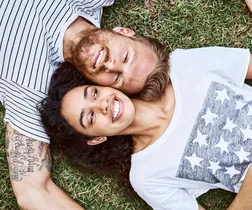 Multi-ethnic couple lying on grass at back yard