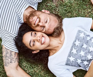 Multi-ethnic couple lying on grass at back yard