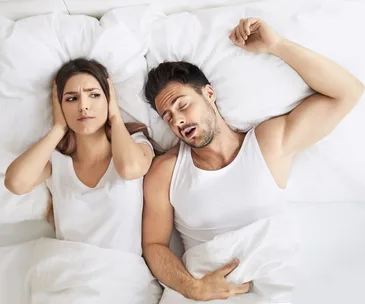Couple in bed, man snoring woman wide awake