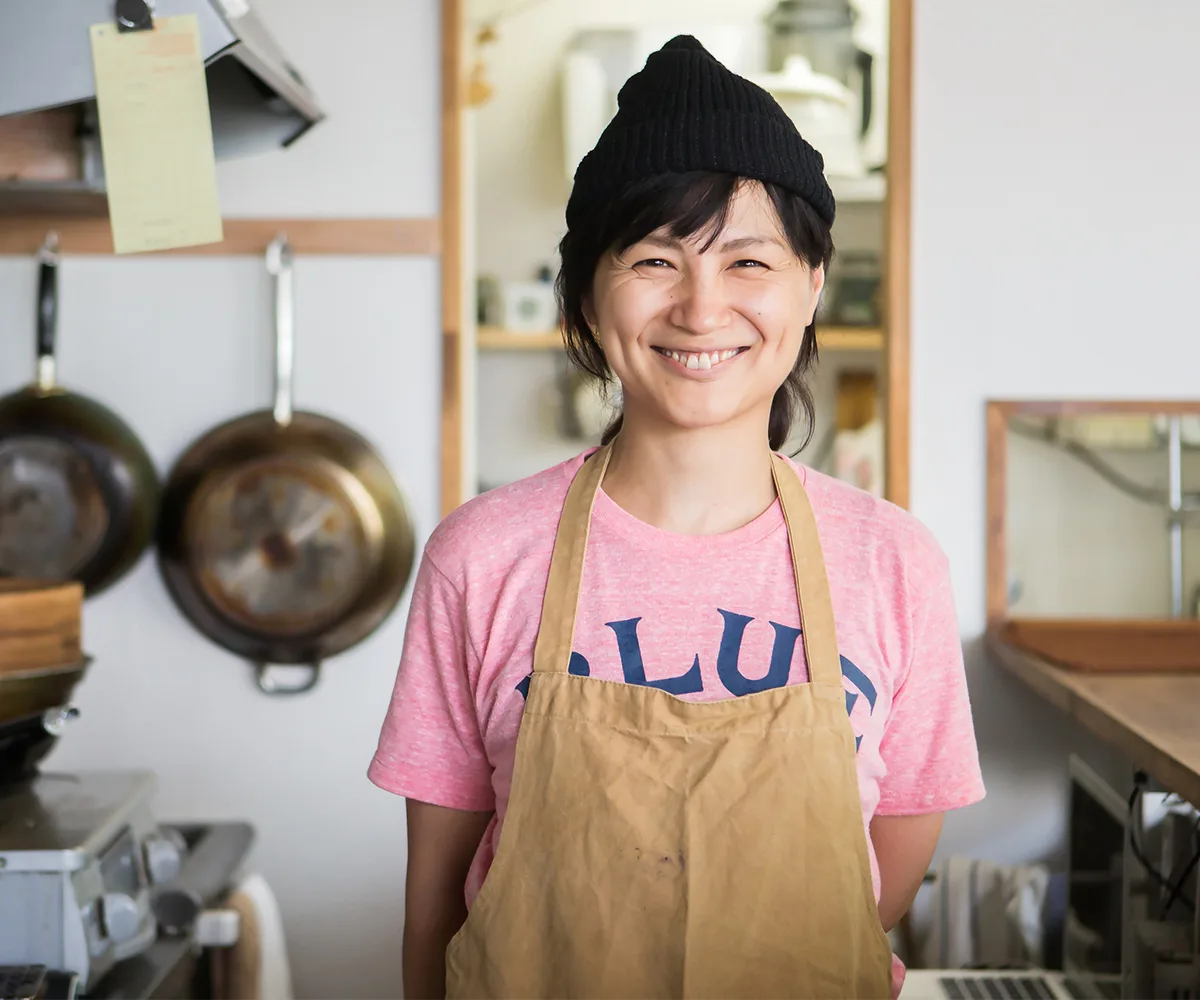 woman business owner stands proudly in the kitchen of her shop