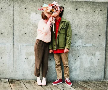couple kissing behind a bouquet