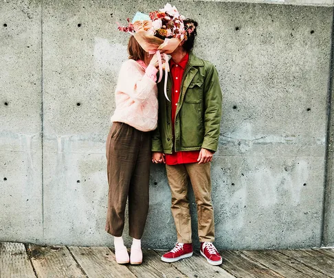 couple kissing behind a bouquet