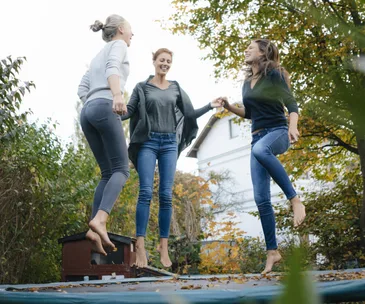 Three women bouncing on trmapoline