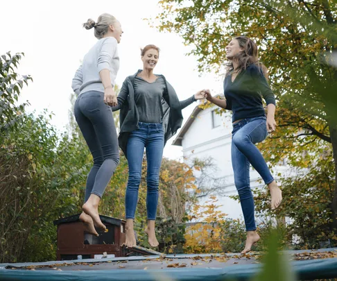 Three women bouncing on trmapoline