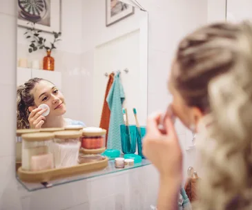 young woman doing skincare routine in bathroom