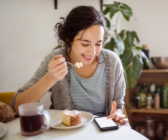 woman eating food looking at phone