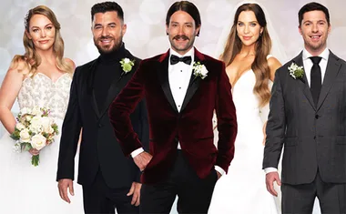 A group of five people dressed in wedding attire, including two women in bridal gowns and three men in tuxedos.